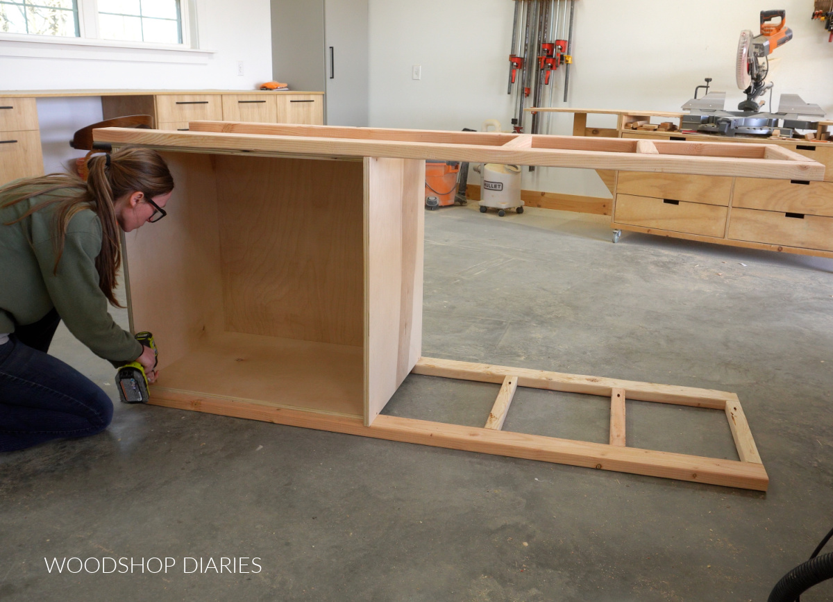 Shara Woodshop Diaries securing cabinet box to shelf frame on workshop floor