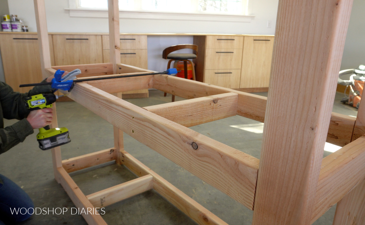 Shara Woodshop Diaries screwing middle supports into shelf frame with wood screws