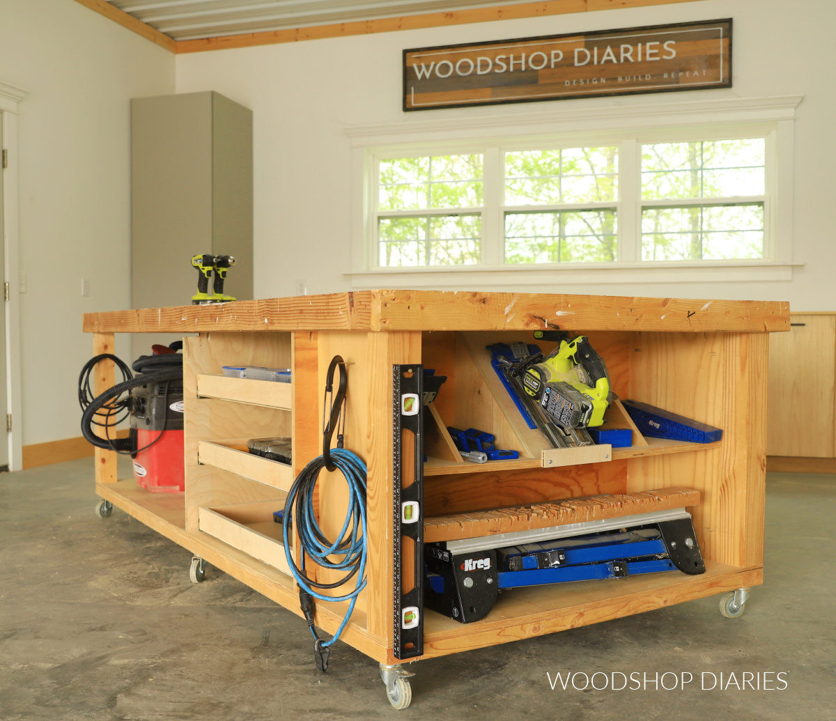 Completed DIY mobile workbench with storage shelf and cubbies on one end and drawers in the middle