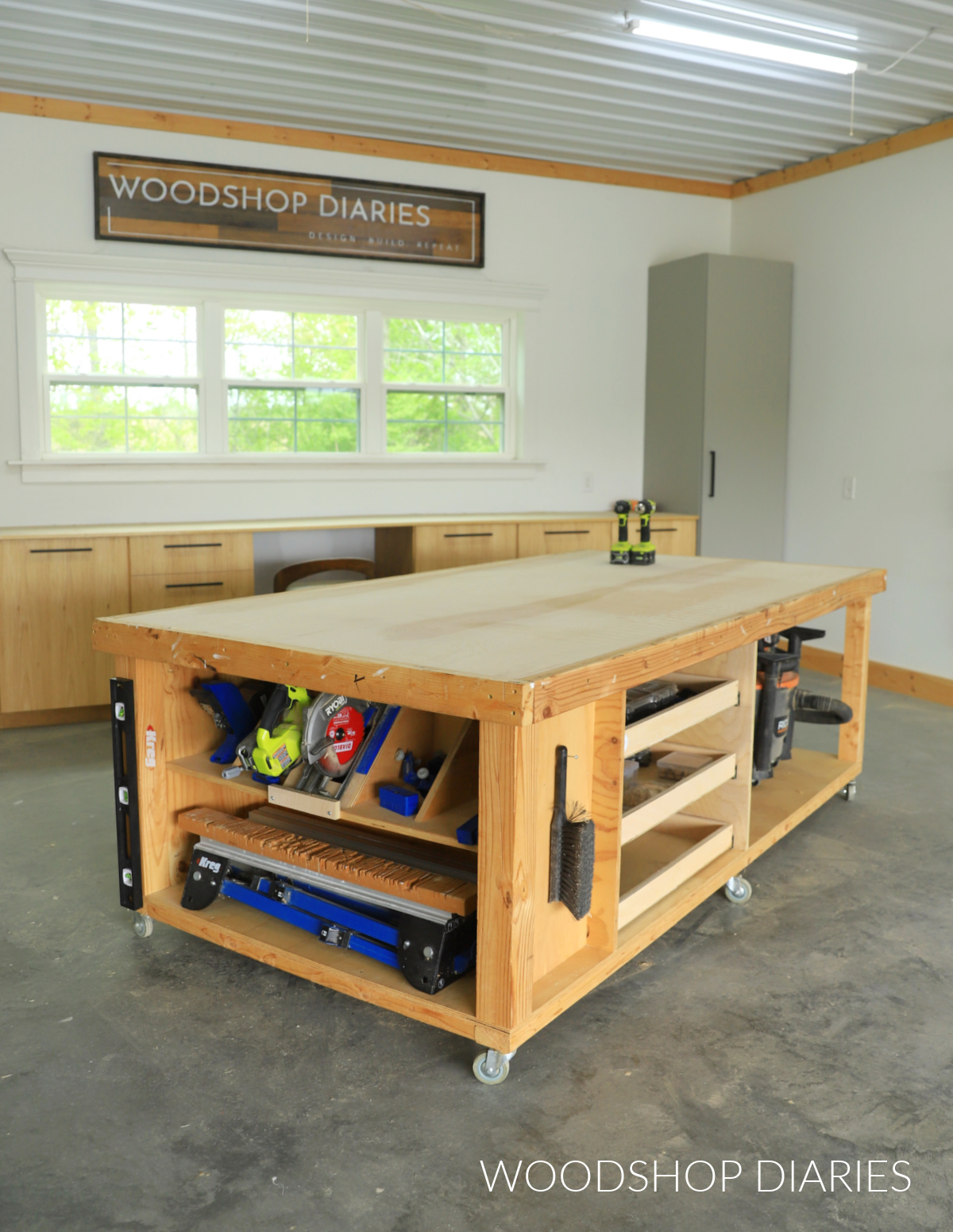 Large mobile workbench with storage shelf and drawers in workshop against wall of cabinets
