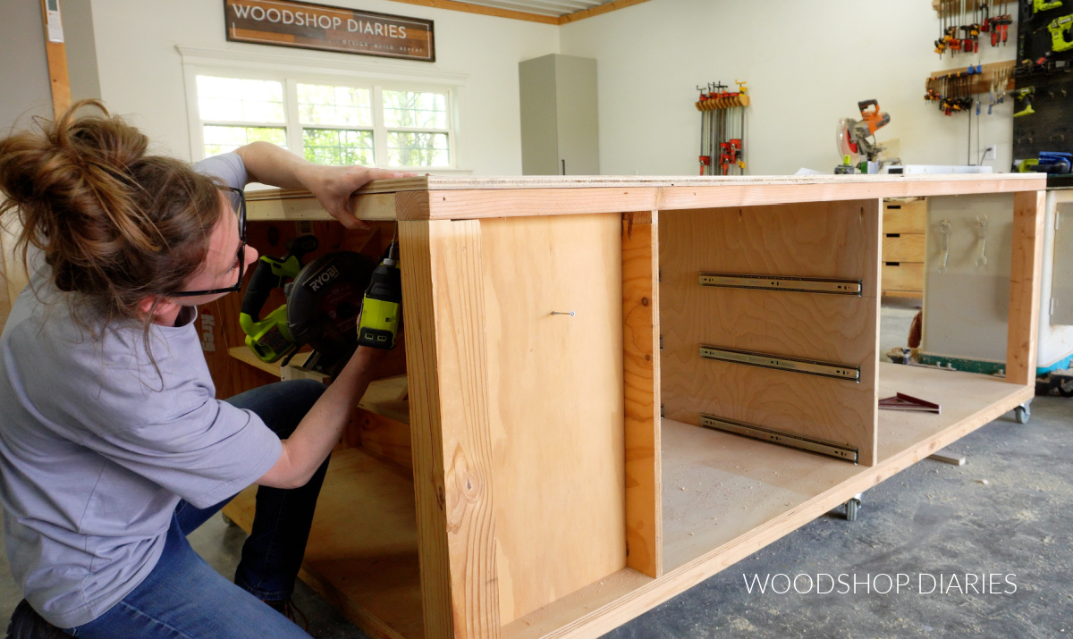 Shara Woodshop Diaries securing top panel to top frame of workbench from bottom side