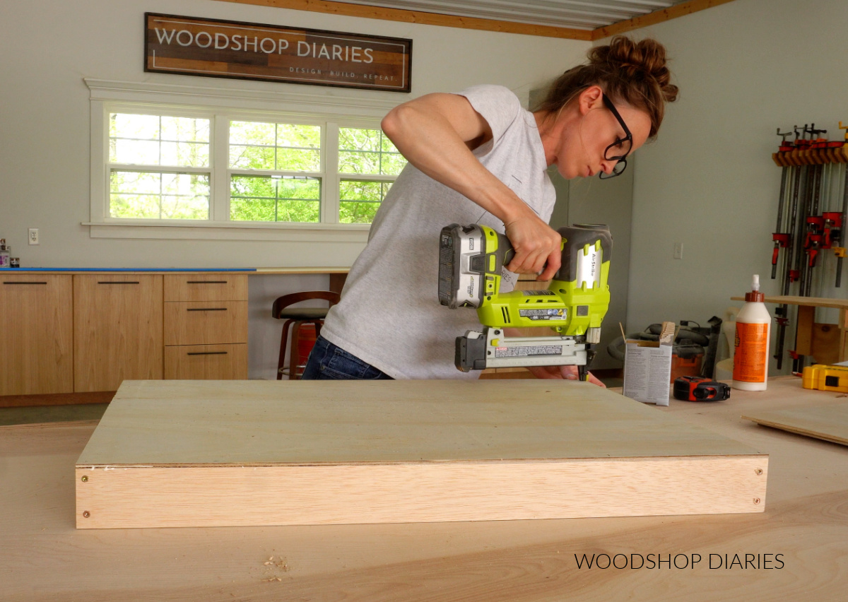 Shara Woodshop Diaries stapling drawer bottoms onto drawer boxes in workshop