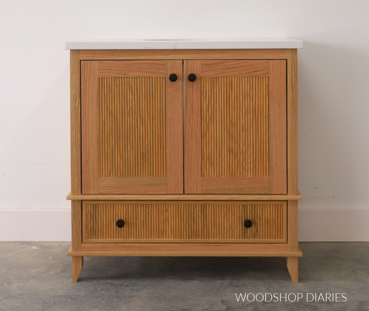 Red oak bathroom vanity with drawer on bottom and two doors on top with fluted trim detail