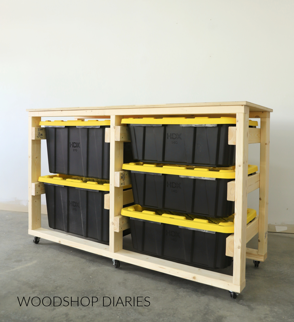 DIY mobile tote storage workbench made from 2x4s and plywood--three large black totes with yellow lids in the left side and three smaller black totes with yellow lids in the right side