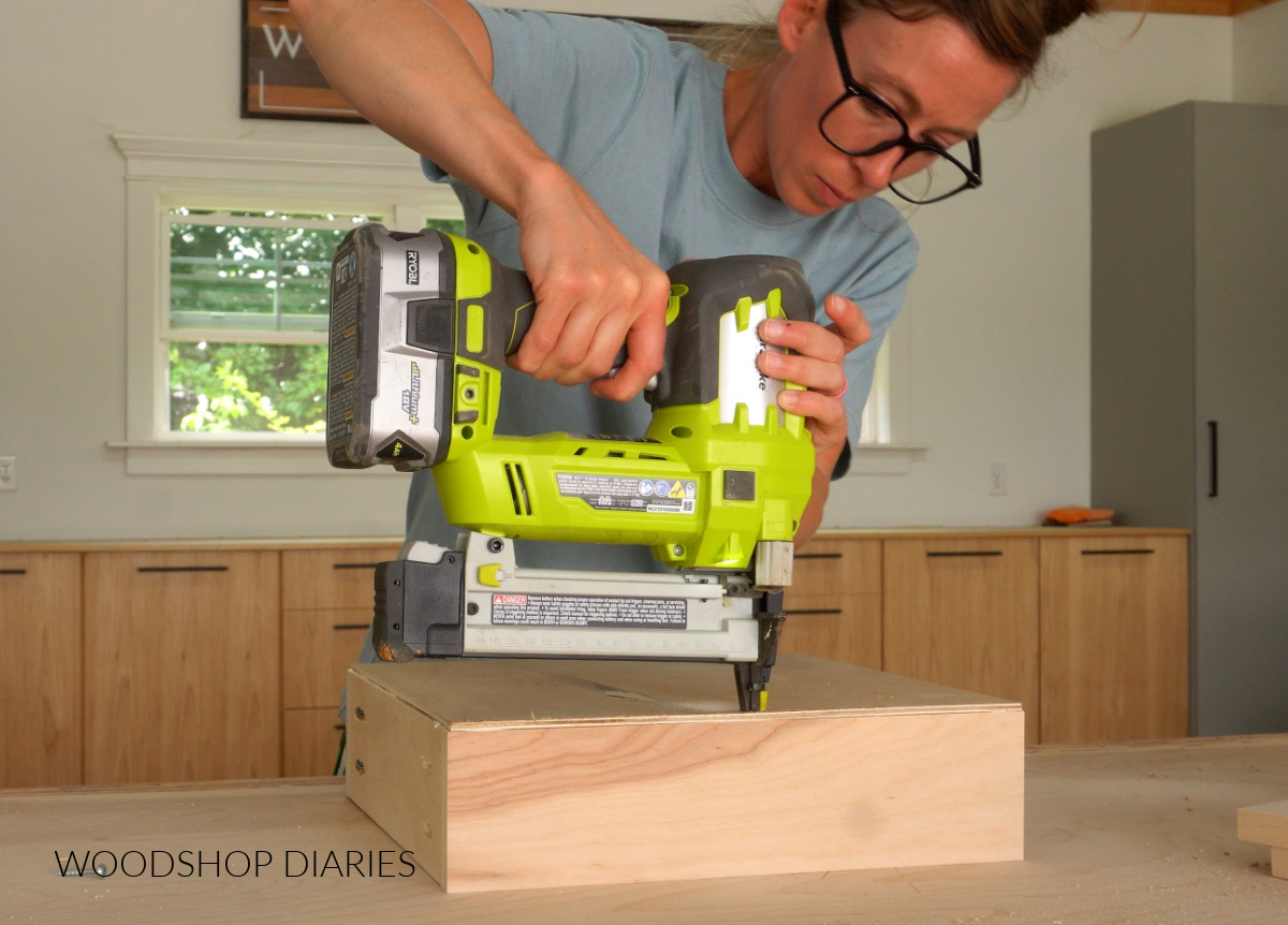 Shara Woodshop Diaries stapling drawer bottoms onto drawer boxes on workbench