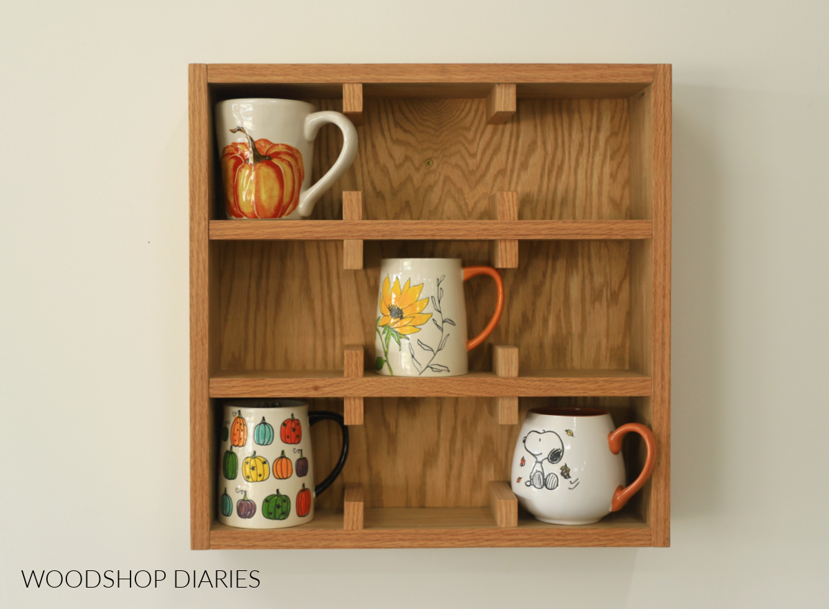 Completed DIY wall mounted mug display shelf made from scrap plywood with four mugs