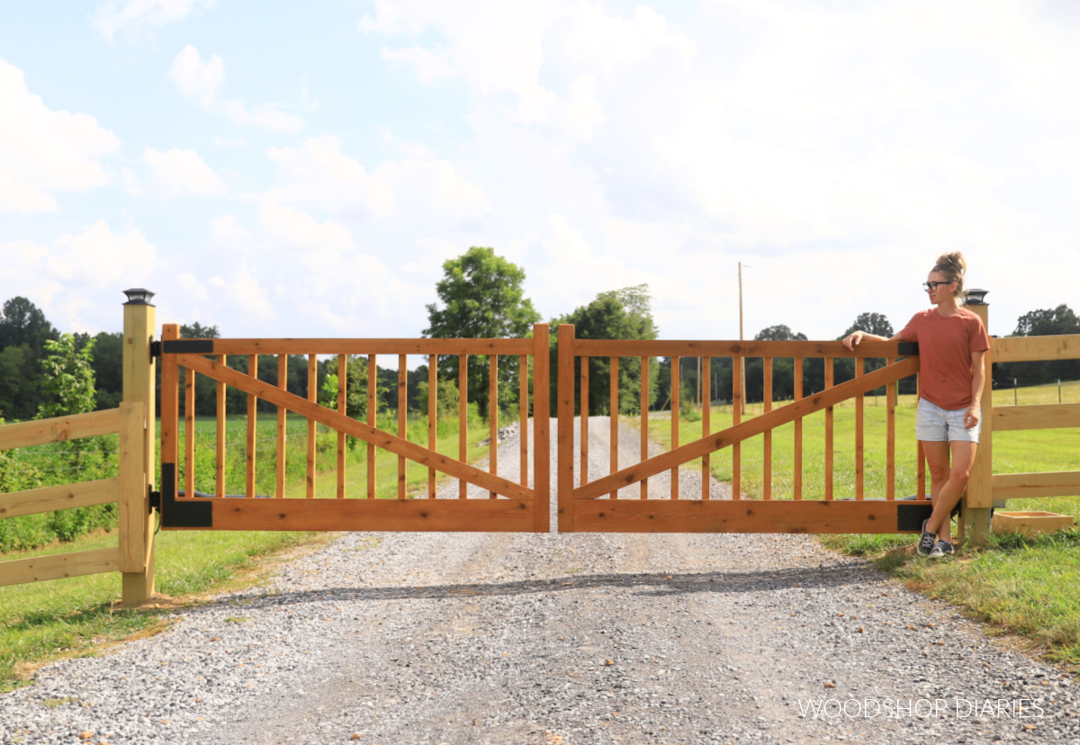 Shara Woodshop Diaries standing next to DIY wooden driveway gates on gravel