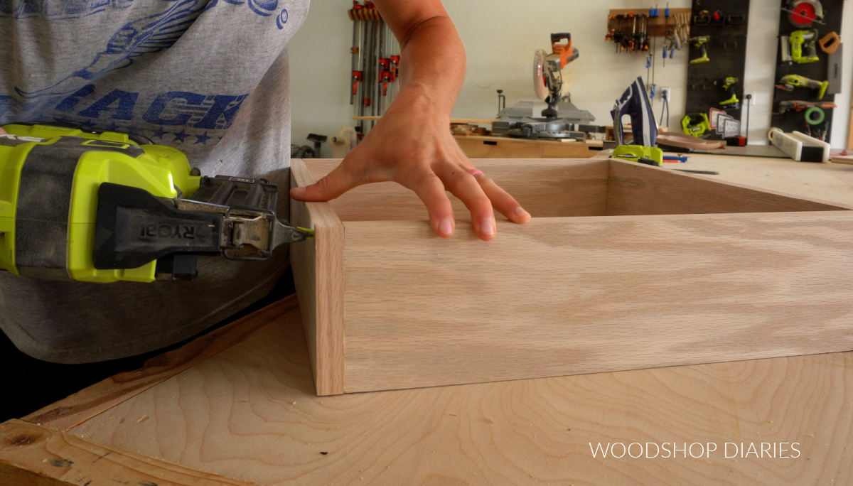 Close up of brad nailing corners of plywood box together on workbench