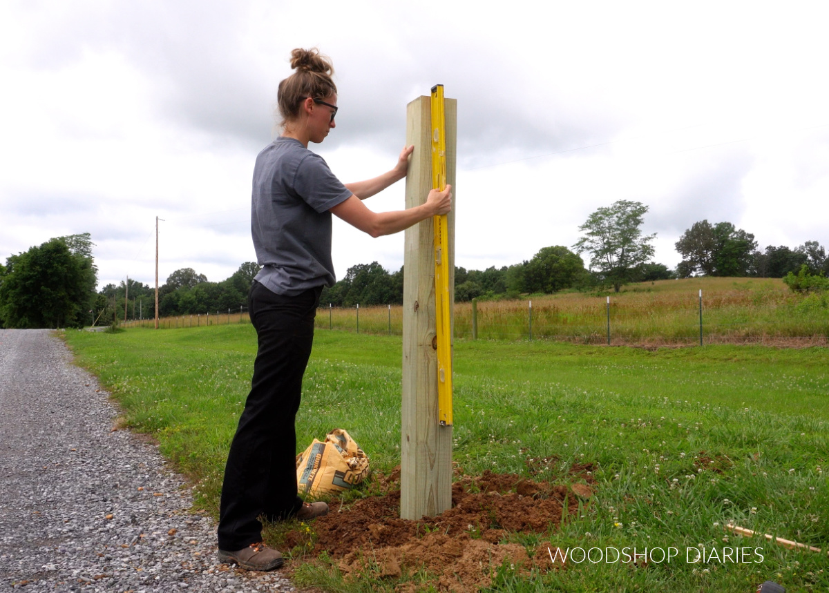 Shara Woodshop Diaries checking that 6x6 gate post is level in ground