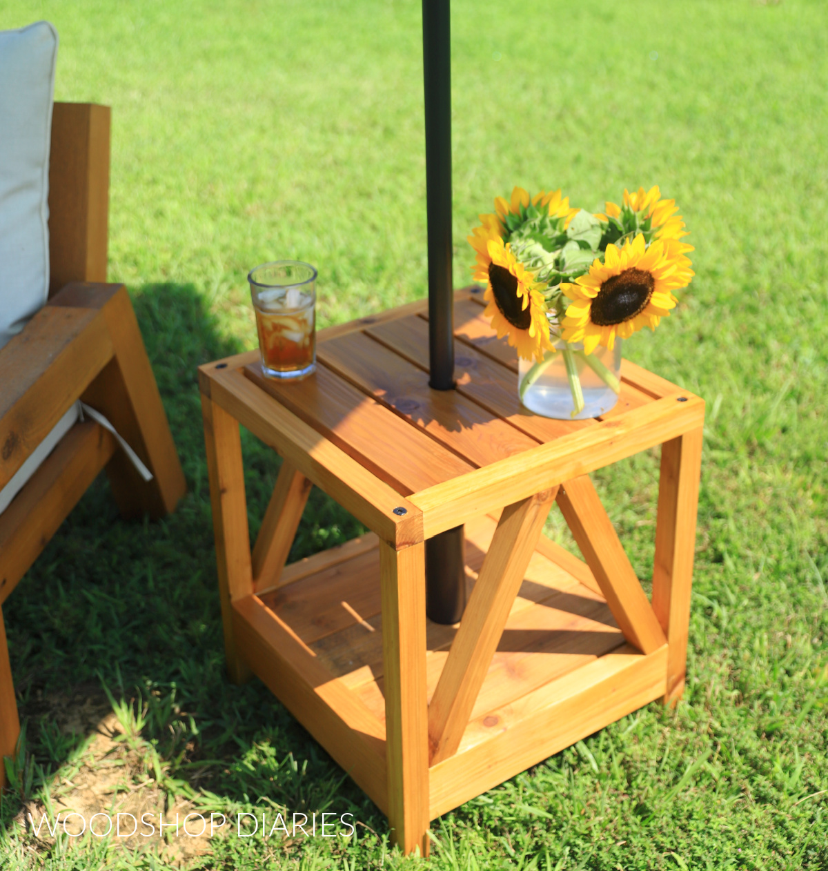 Close up of top of DIY wooden umbrella stand side table with sunflowers and iced tea