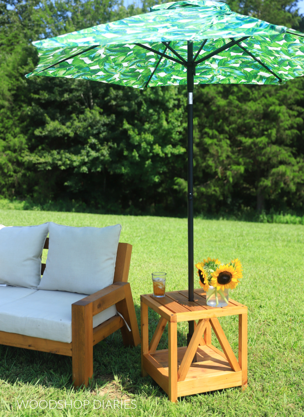 Umbrella stand side table with palm leaf umbrella sitting next to outdoor sofa