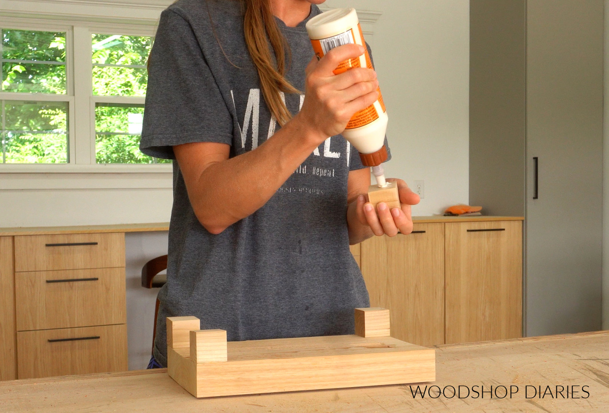 Shara Woodshop Diaries applying glue to wooden cubes to glue onto cedar board