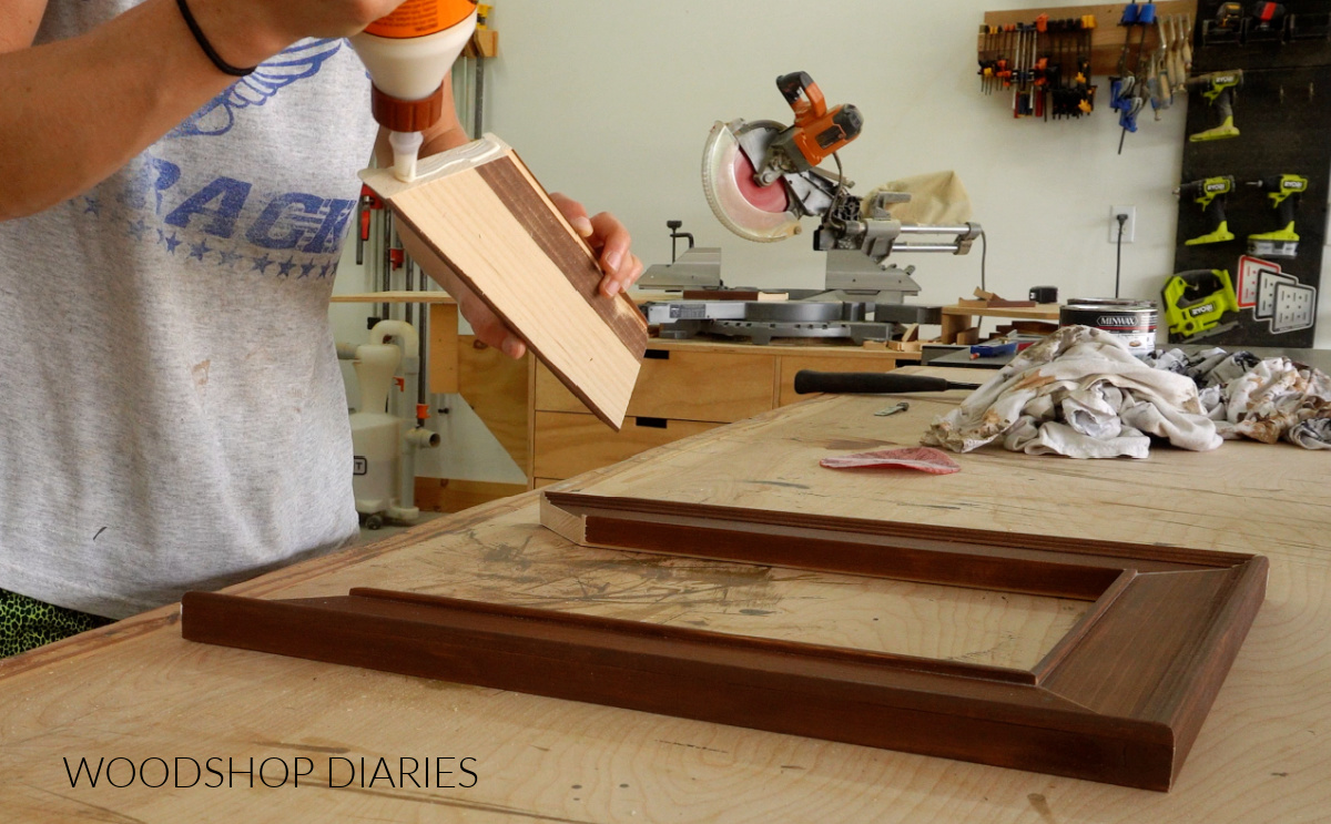 Applying wood glue to ends of picture frame pieces to assemble