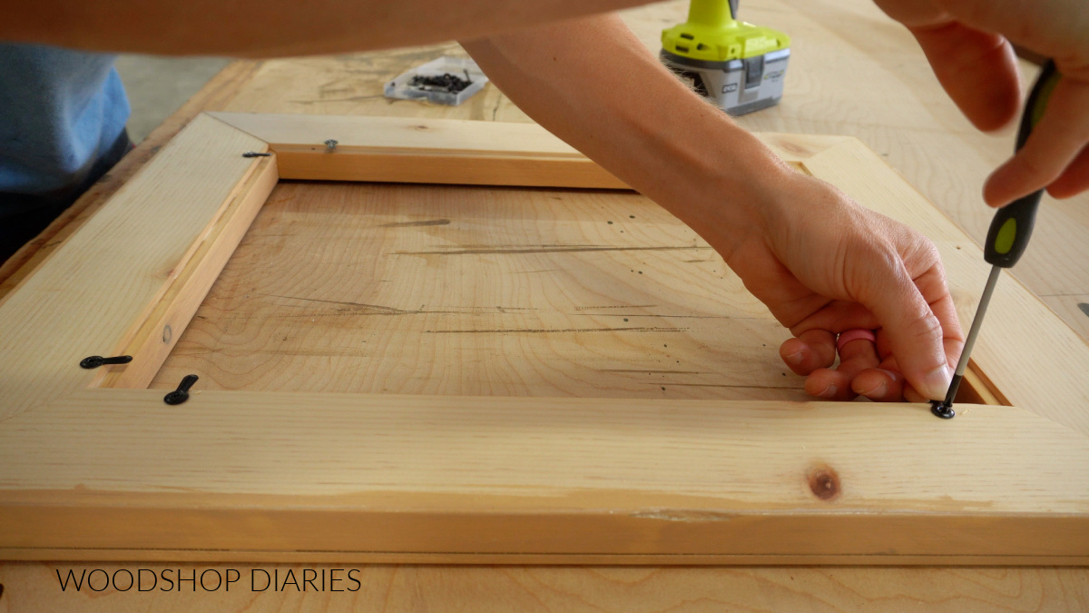 Installing turn buttons on back of wooden picture frame with screwdriver