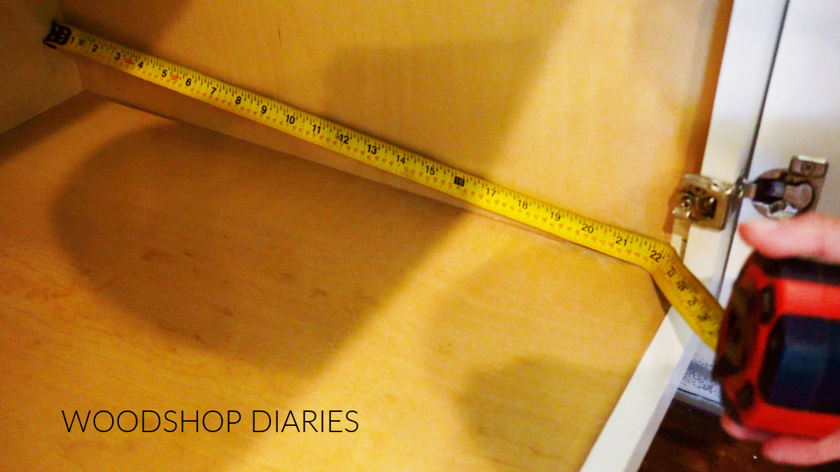 Tape measure measuring cabinet depth inside cabinet