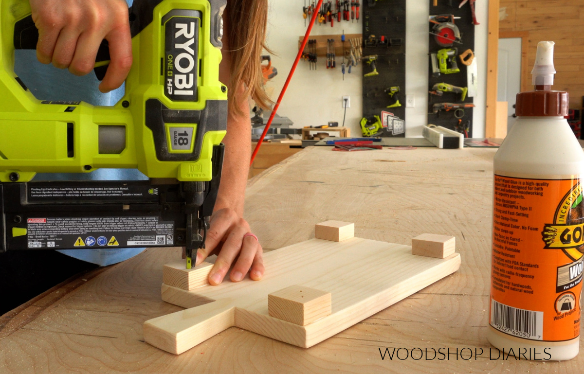 Shara Woodshop Diaries gluing and nailing scrap boards onto bottom of pine board with handle cut out