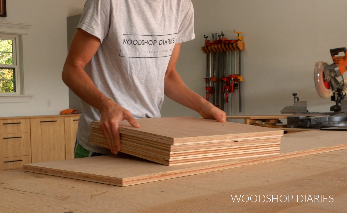 Shara Woodshop Diaries placing plywood squares in stack on workbench