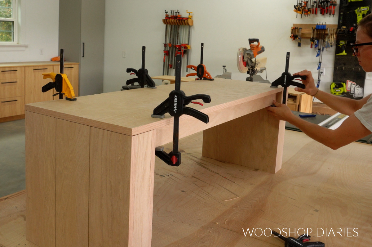 Shara Woodshop Diaries clamping plywood bench top to chunky modern bench base on workbench