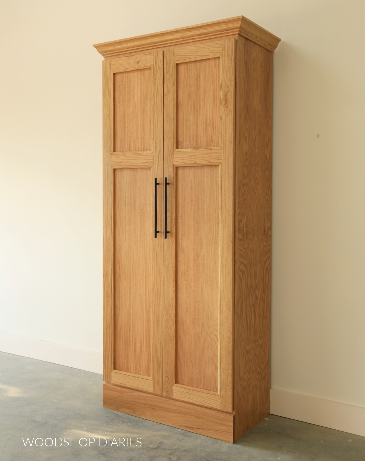 Completed red oak wardrobe cabinet with double doors and crown molding