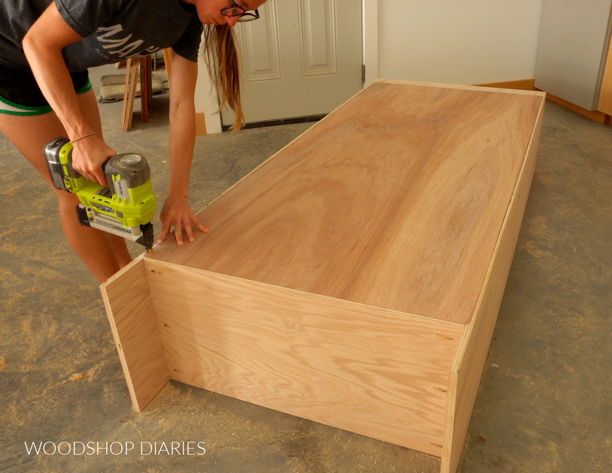 Shara Woodshop Diaries stapling ¼" plywood back panel onto tall storage cabinet
