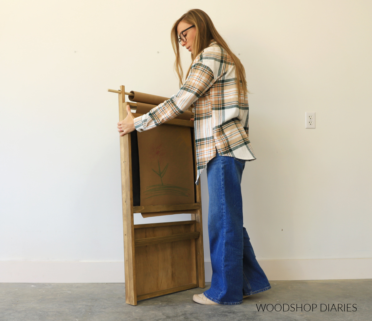 Shara Woodshop Diaries holding folded up DIY art easel with tray