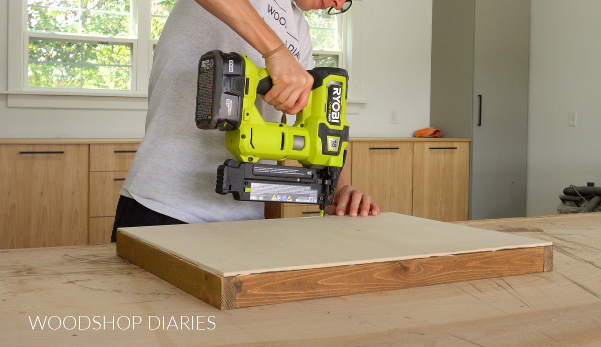 Shara Woodshop Diaries brad nailing easel tray together on workbench