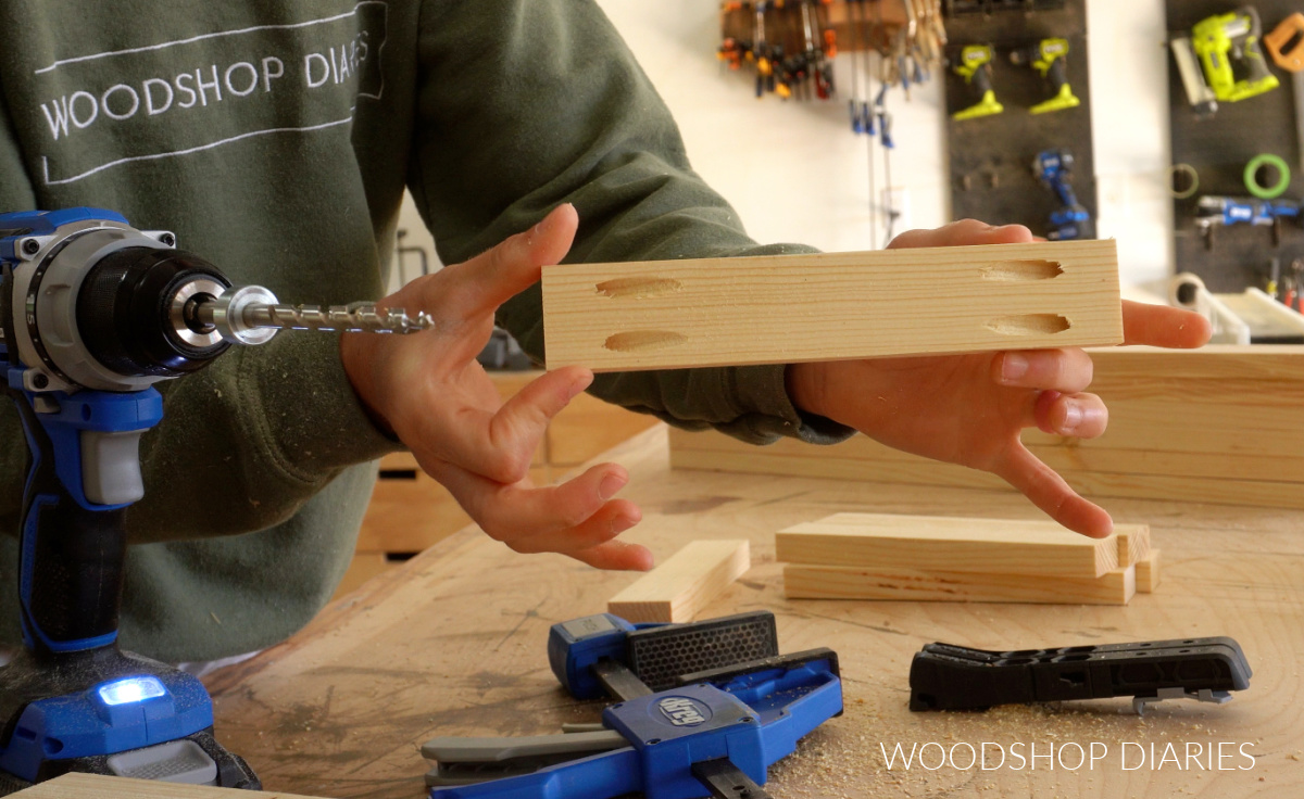 Shara Woodshop Diaries holding up 1x2 board with pocket holes drilled in each end