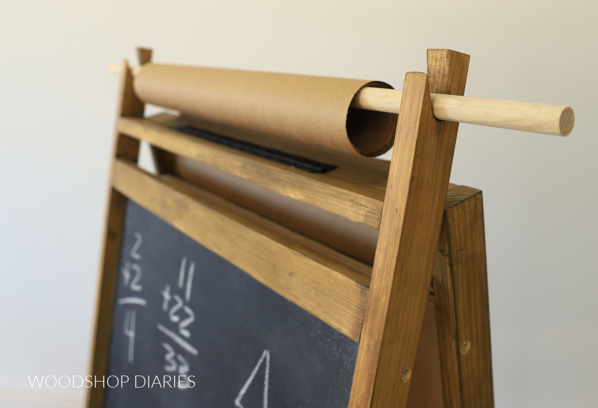 Close up of DIY art easel paper roll dowel placed in notches on frame