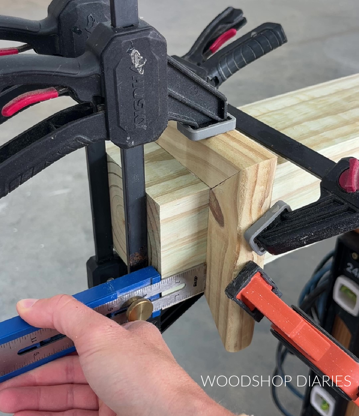 Close up of clamps holding trim around top of lamp post while glue dries