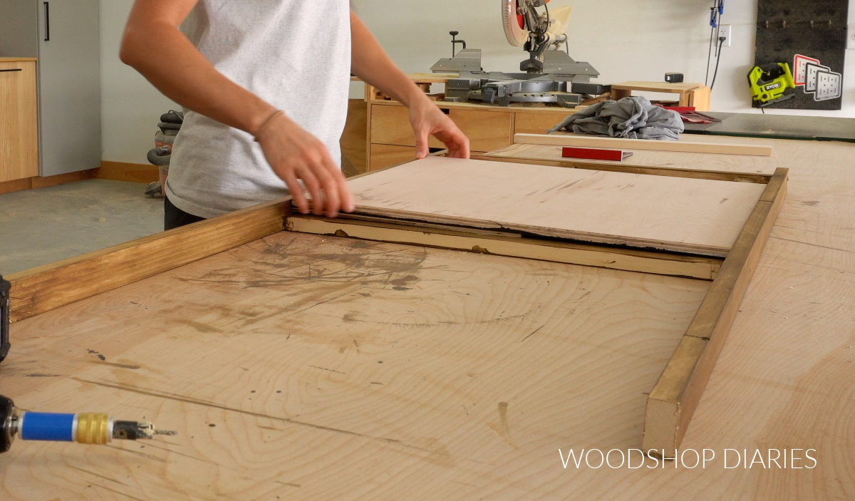 Shara Woodshop Diaries placing chalkboard canvas into art easel frame on workbench