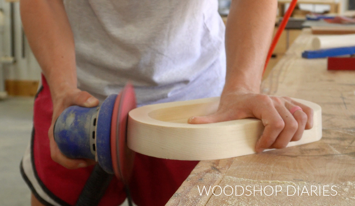 Close up of Shara Woodshop Diaries sanding catch all tray edges with orbital sander