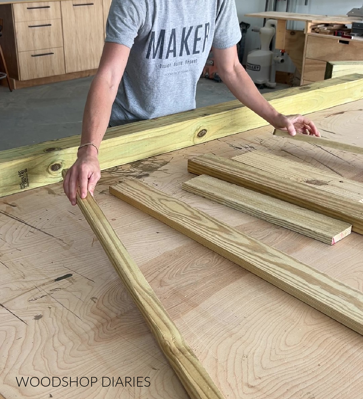 Shara Woodshop Diaries laying out scrap treated wood on workbench