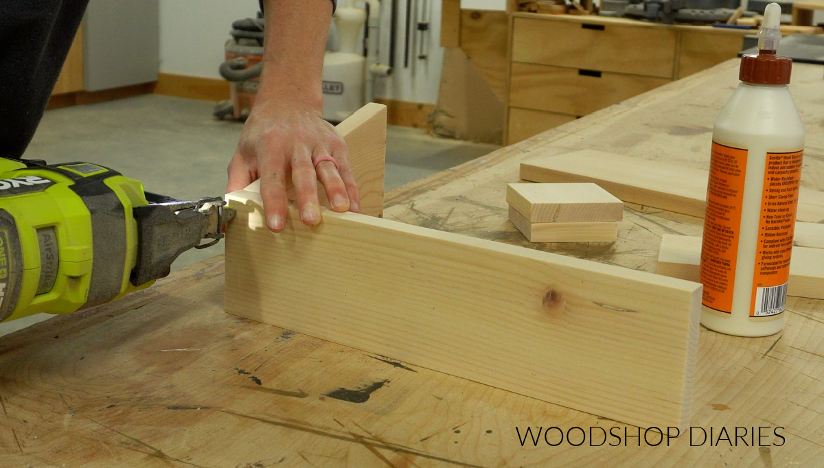 Shara Woodshop Diaries nailing dinnerware caddy together on workbench