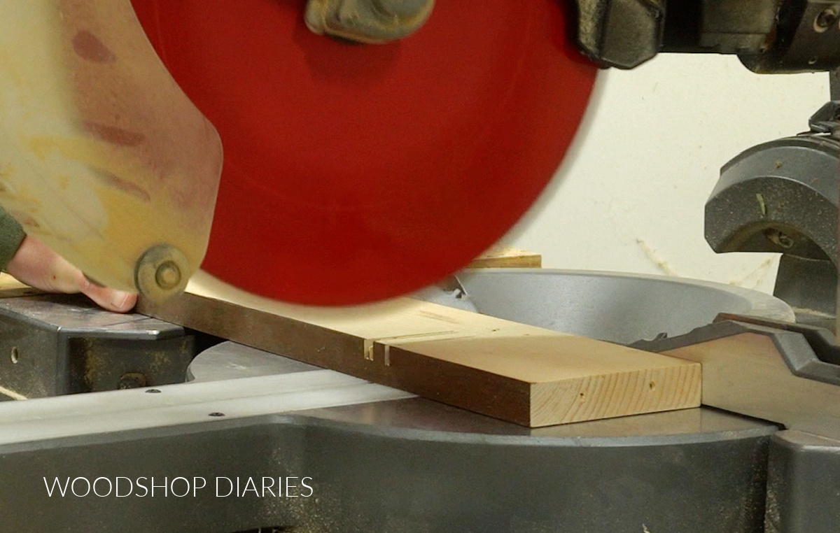 Close up of miter saw cutting notch in scrap wooden trivet jig