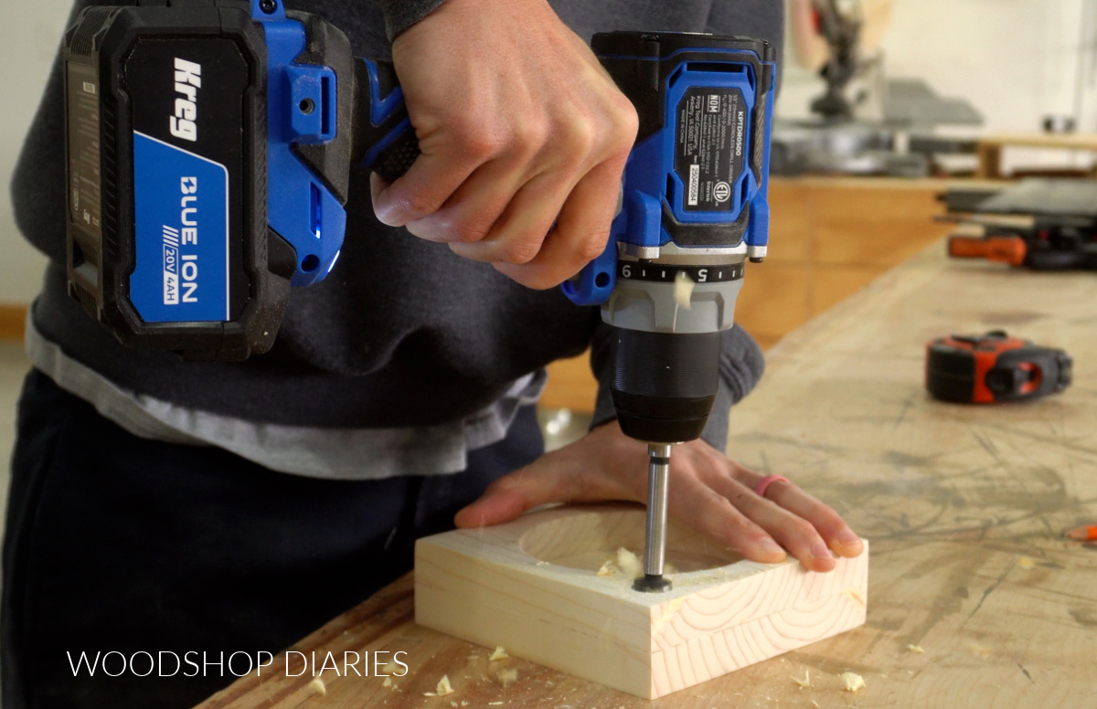 Close up of Shara Woodshop Diaries drilling hole in cup holder to hold marker