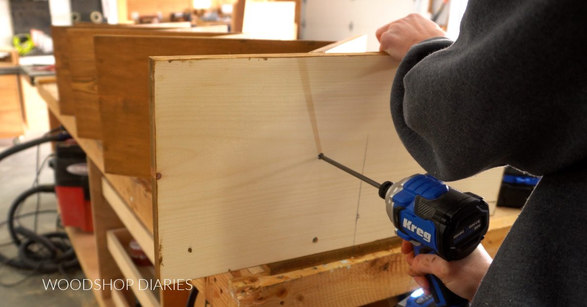 Shara Woodshop Diaries driving screw to secure bottom of angled shelf