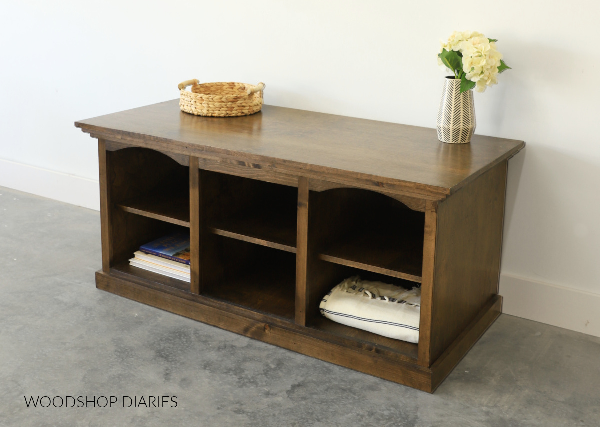 Dark brown stained DIY TV stand console with arches in top of face frame. Open shelves with books and blankets