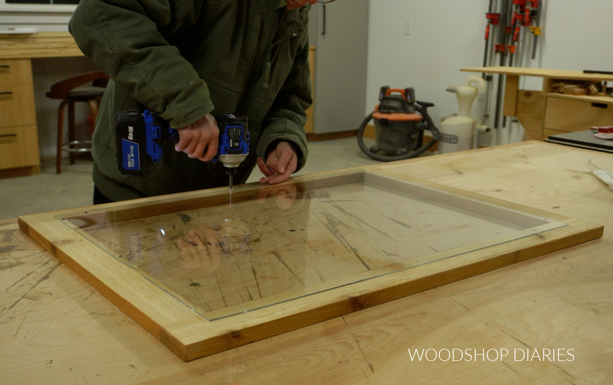 Shara Woodshop Diaries securing acrylic panel to door frame using screws from the back side