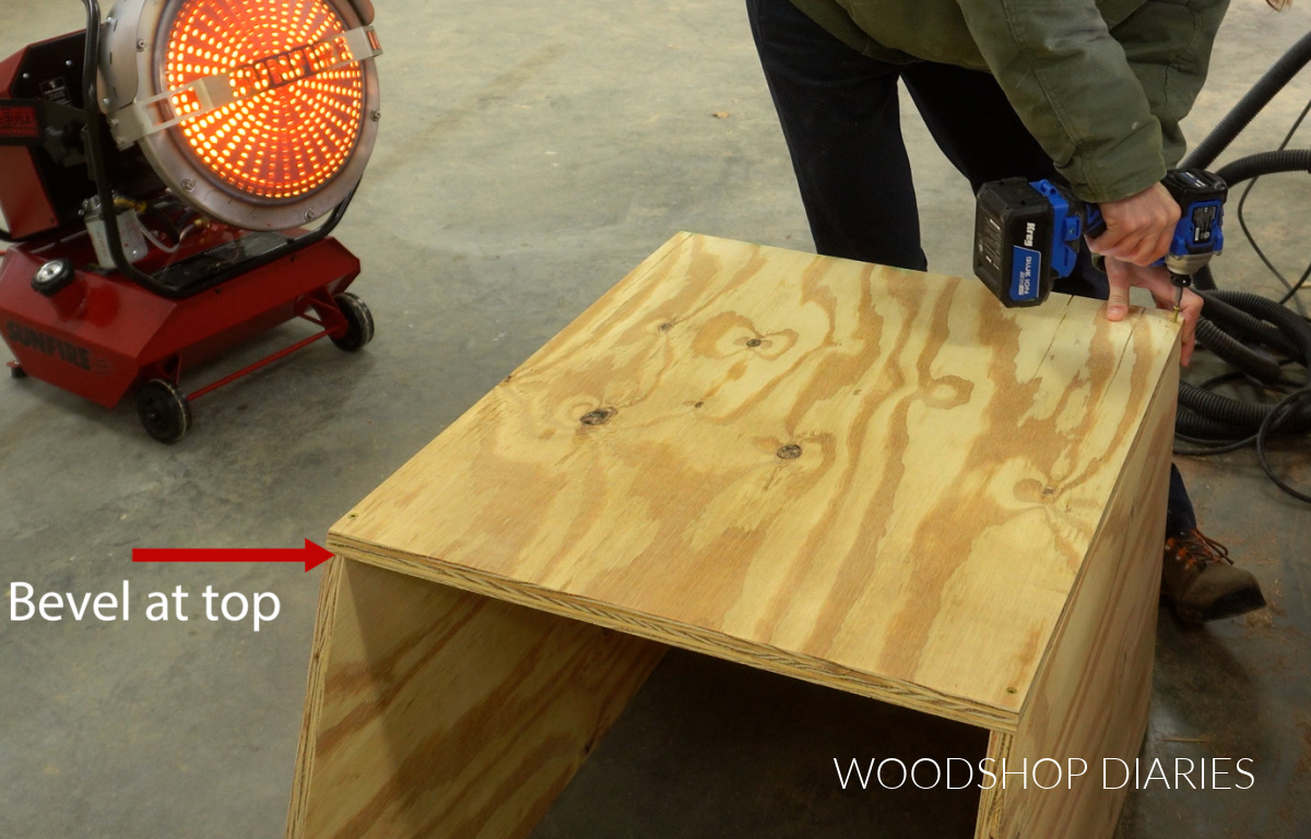 Shara Woodshop Diaries screwing back panel onto community pantry box on workshop floor