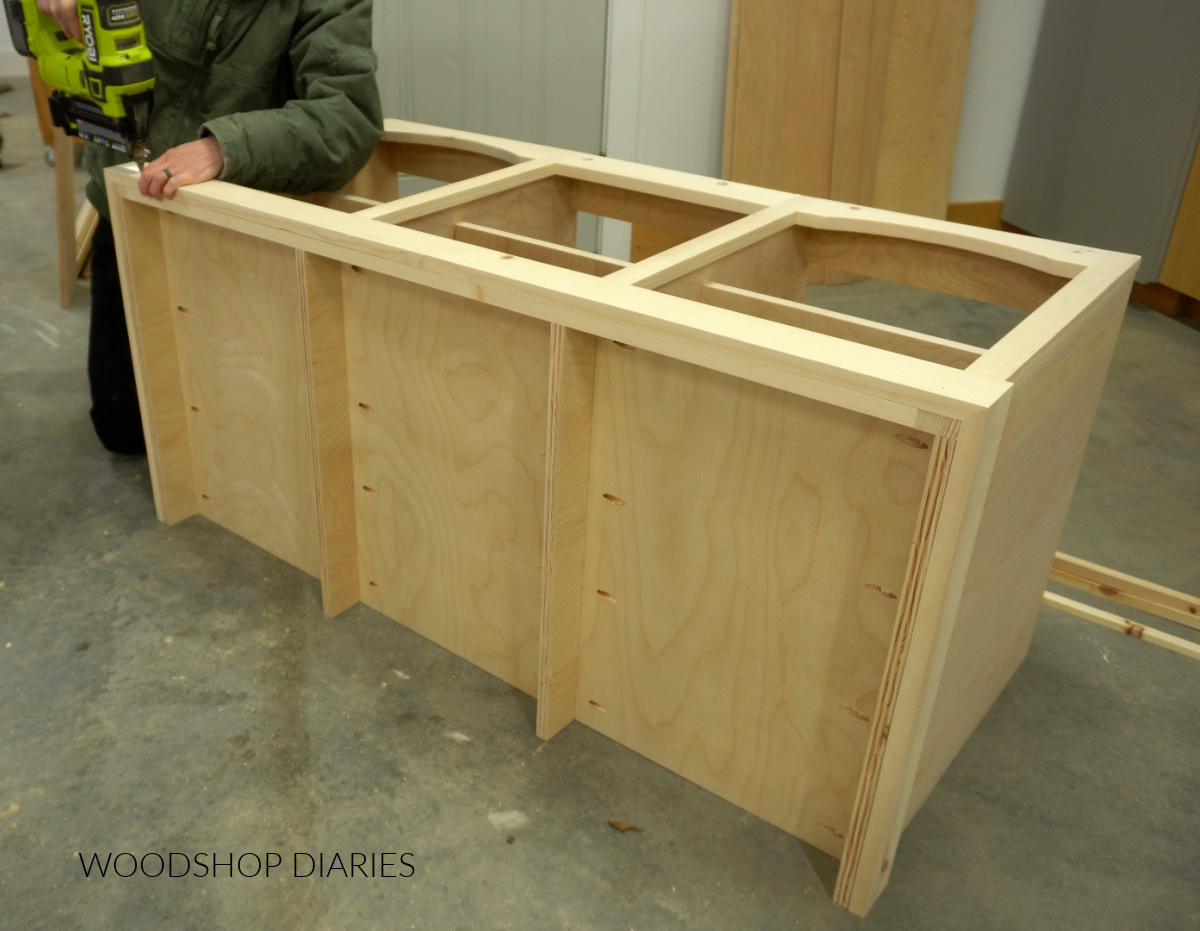 Shara Woodshop Diaries brad nailing 1x3 trim around bottom of tv stand build in workshop