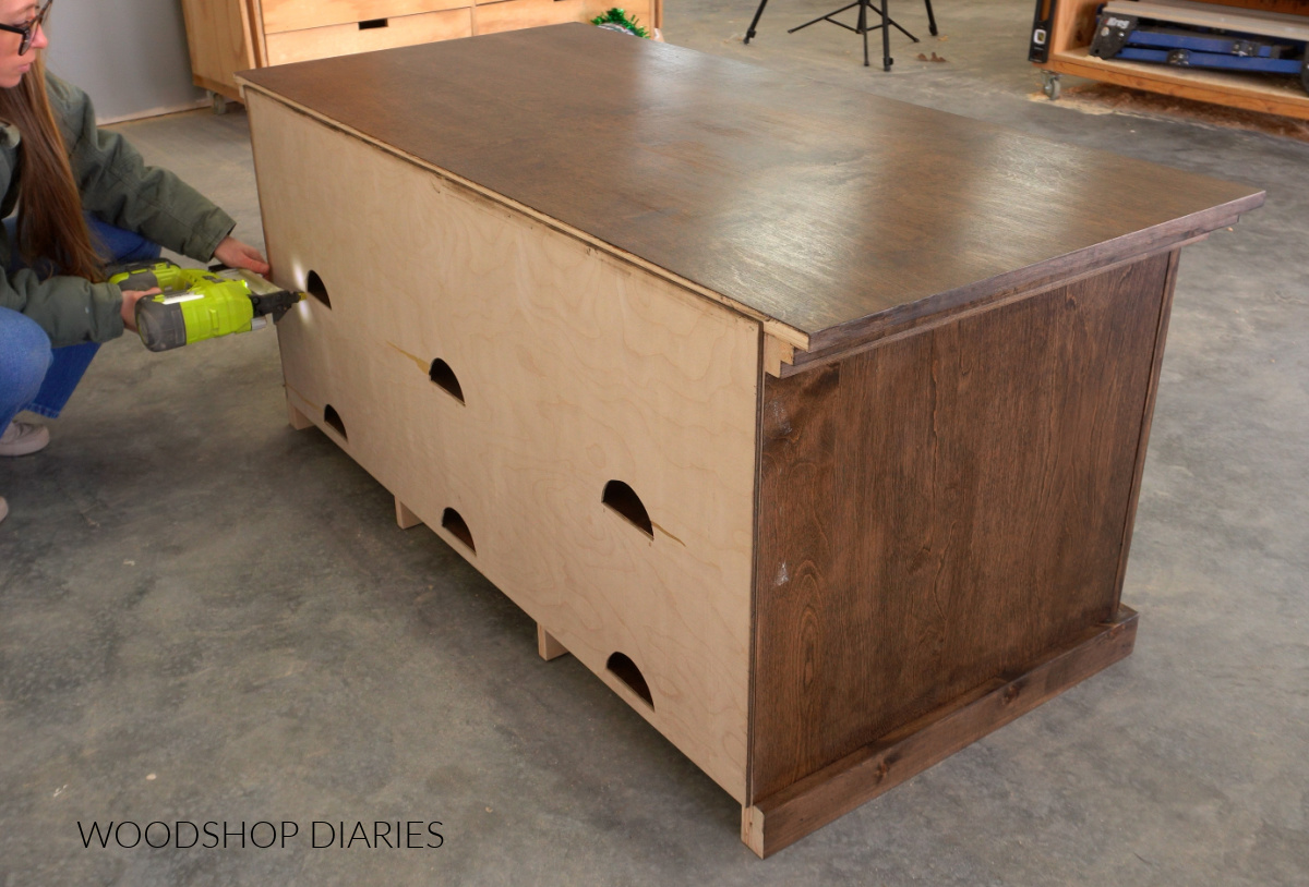 Shara Woodshop Diaries stapling back panel onto TV stand project