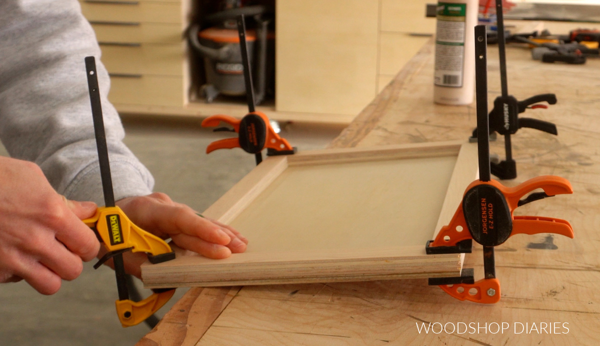 Close up of Shara Woodshop Diaries clamping sides around drawers for puzzle board