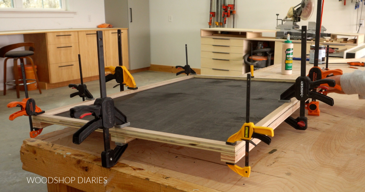 ½" plywood strips glued and clamped around top of puzzle board on workbench