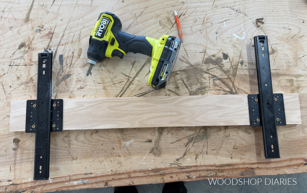 Pocket door hardware slides mounted to plywood strip on workbench