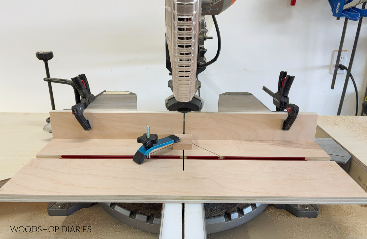 Small parts jig clamped into miter saw with small block inside ready to cut