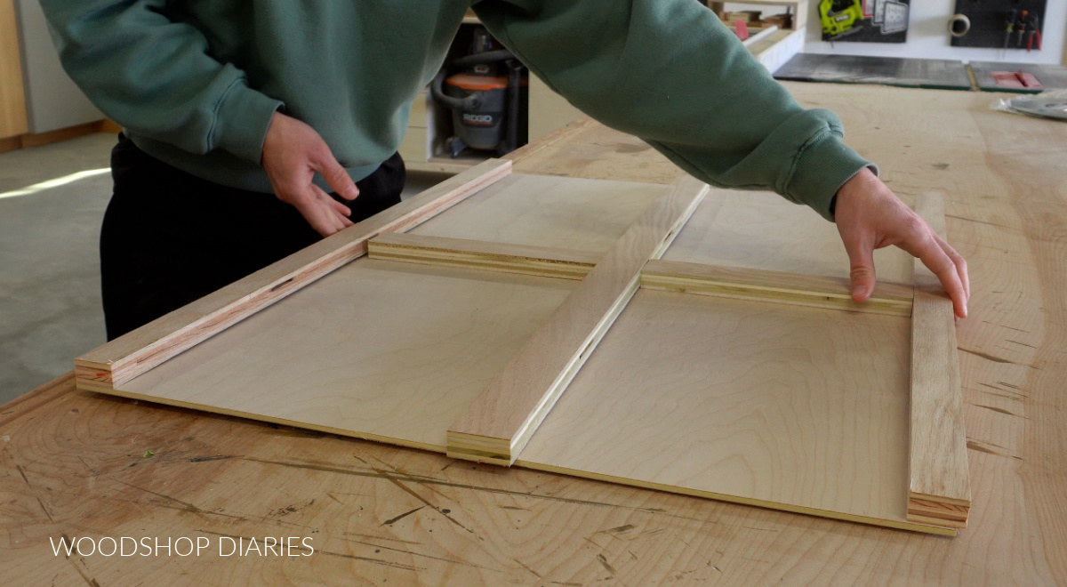 Shara Woodshop Diaries fitting puzzle board framing pieces onto puzzle board top on workbench