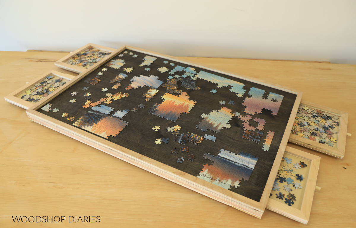 Completed DIY puzzle board with drawers open. Puzzle pieces stored in drawers
