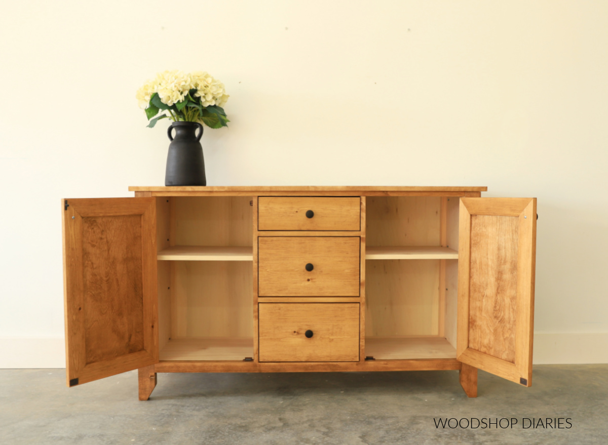DIY wooden buffet console cabinet with two doors open to show shelving inside. Three drawers in middle section