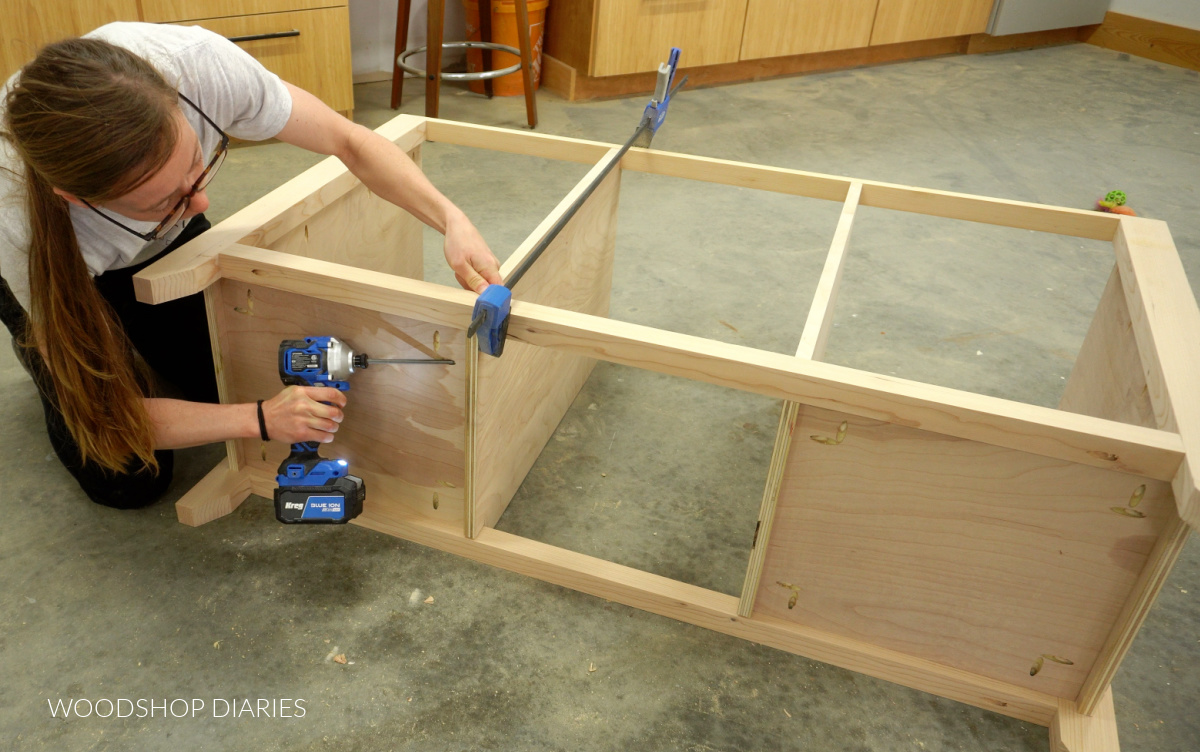 Shara Woodshop Diaries installing bottom panels of buffet console with pocket holes on workshop floor