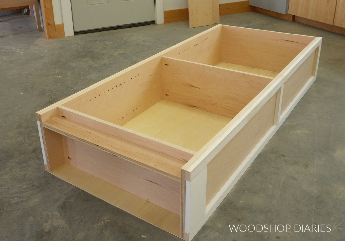 Bookcase laid on its back on workshop floor with prime pine trim added to sides